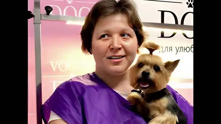 Жінка з короткою зачіскою притулила до фіолетової форми підстриженого йорка з топ кнотом