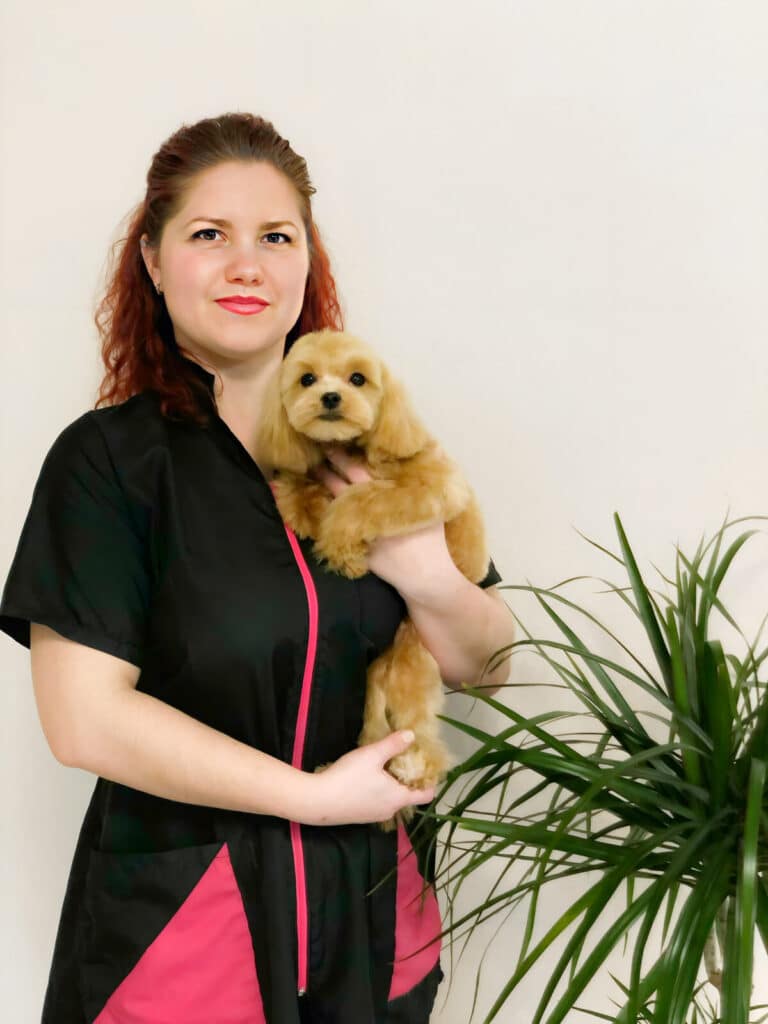 Жінка з рожевою помадою притисла до грудей маленького мальтіпу золотистого кольору