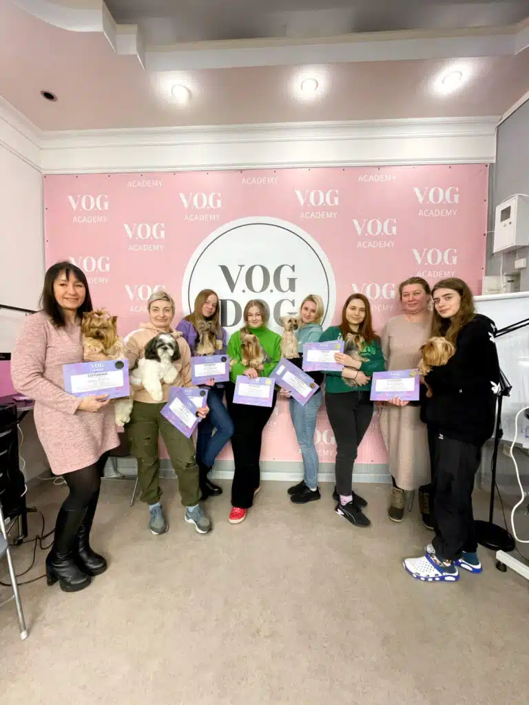 Разом з викладачем в бежевій сукні стоять вдячні випускники з собаками та сертифікатами в руках