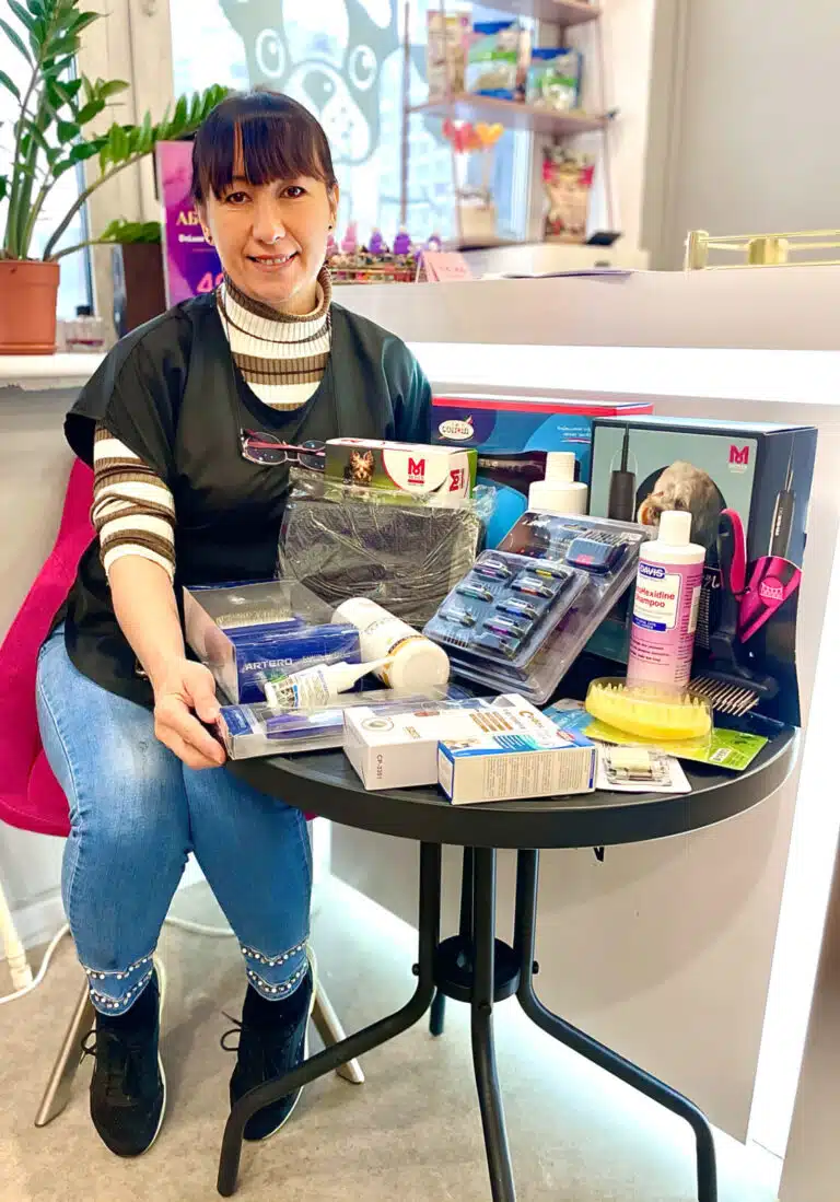 Дівчина з гривкою на голові сидить поруч зі столом, на якому лежать інструменти та косметика для грумінгу