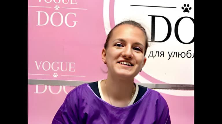 Дівчина з піднятою головою вдягнута в фіолетову накидку та чорну футболку з білим комірцем