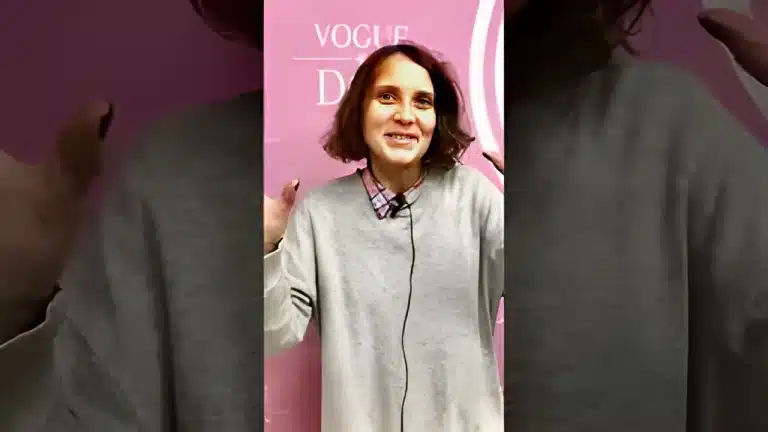 Дівчина у сорочці та бежевій кофті підняла руки з чорним манікюром вверх