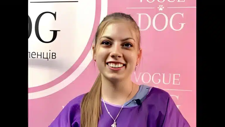 Дівчина з прямим хвостиком має прикрасу на шиї, яка виділяється на фоні фіолетового одягу