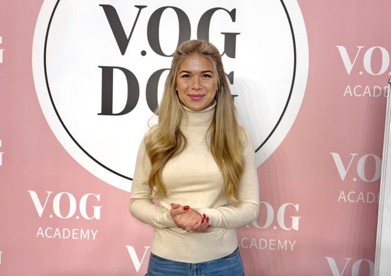 Дівчина з довгим волоссям склала руки з червоним манікюром разом та посміхається на камеру