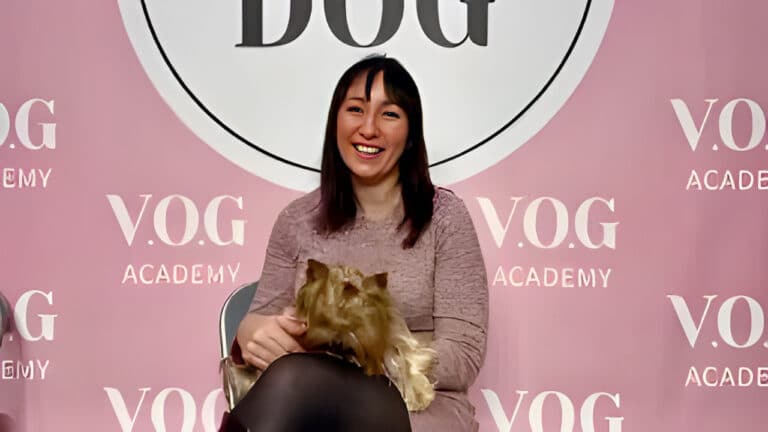 Дівчина в рожевій сукні та чорних панчохах сидить разом з йорком, який дивиться вниз