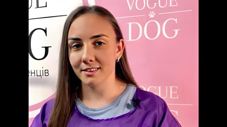 Дівчина з прямим волоссям та втомленим поглядом вдягнута у блакитну футболку та фіолетову накидку