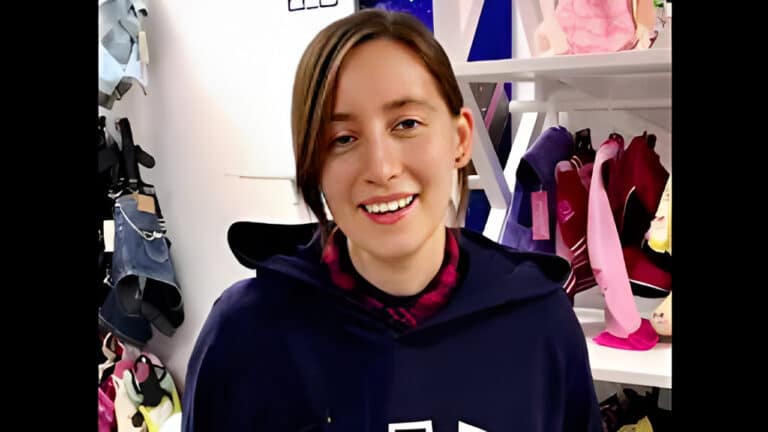 Дівчина з довгою гривкою посміхається фотографу, трохи прикривши очі