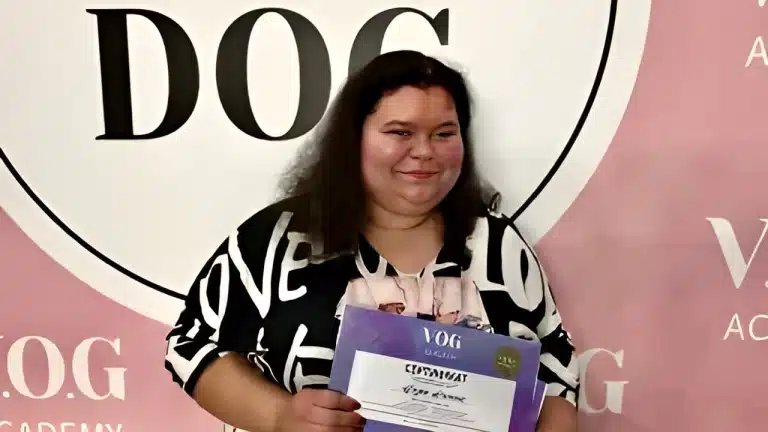 Жінка з кучерявим волоссям тримає в руці фіолетовий сертифікат та має щасливий вигляд