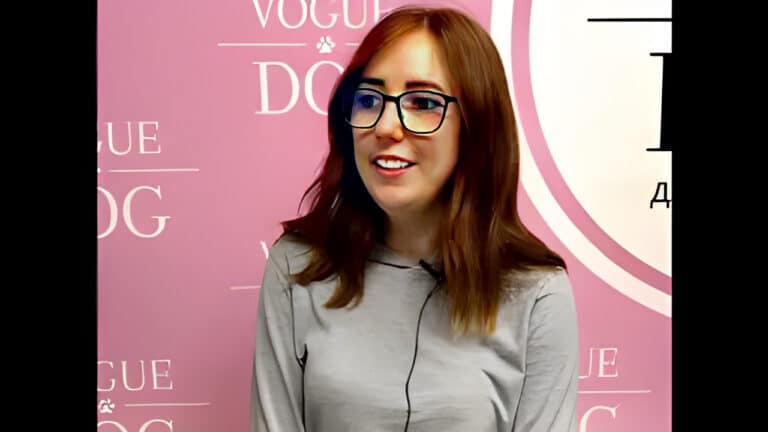 Дівчина в чорний окулярах сором'язливо посміхається під час запису звуку на мікрофон