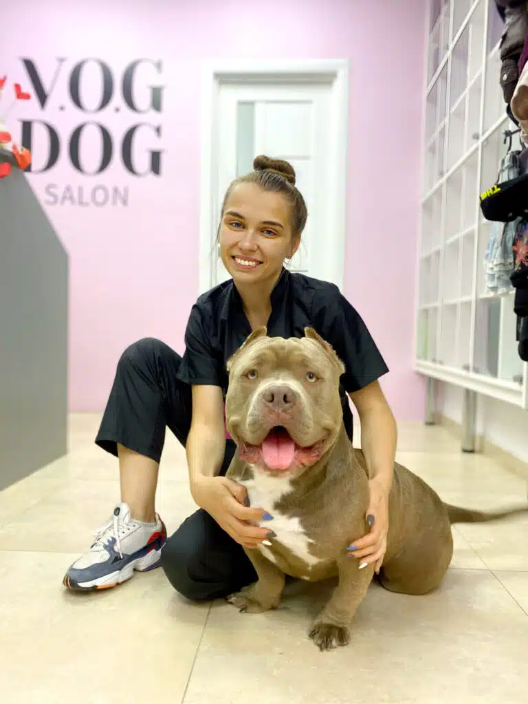 Дівчина у спортивних кросівках присіла біля стаффа з купірованими вушками