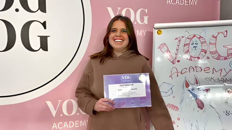 Дівчина в коричневому худі радіє отриманому фіолетовому сертифікату, що тримає в руці