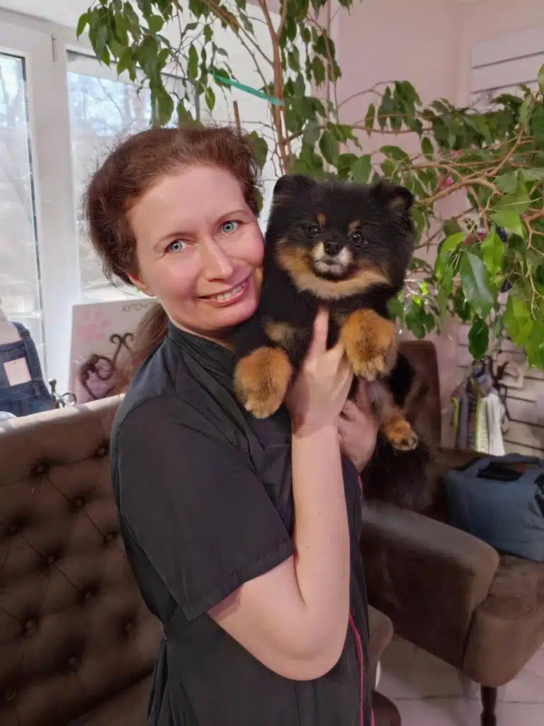 Позаду жінки з темним шпіцом розташувались диван з кріслом та великий вазон