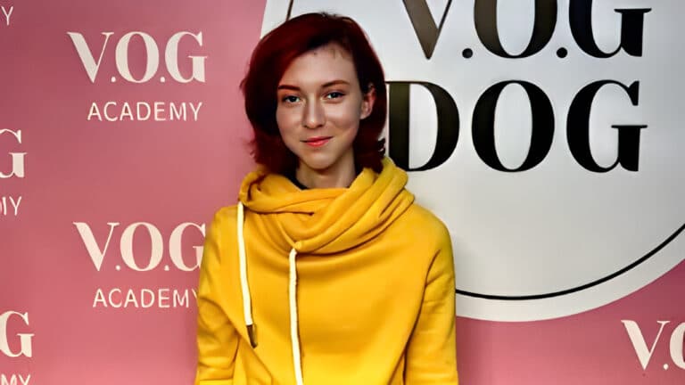 Дівчина з червоним коротким волоссям та персиковою помадою на губах вдягнута в жовте худі