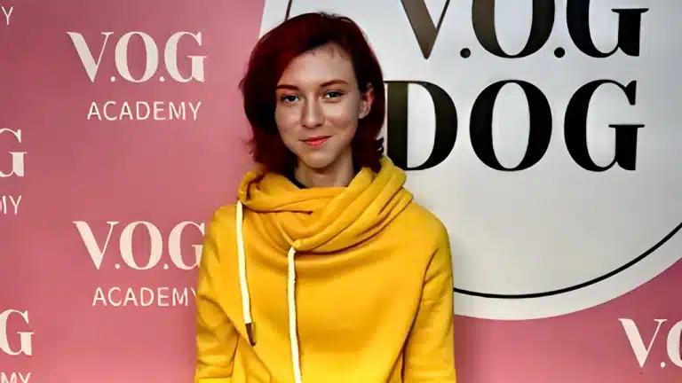 Дівчина з червоним коротким волоссям та персиковою помадою на губах вдягнута в жовте худі