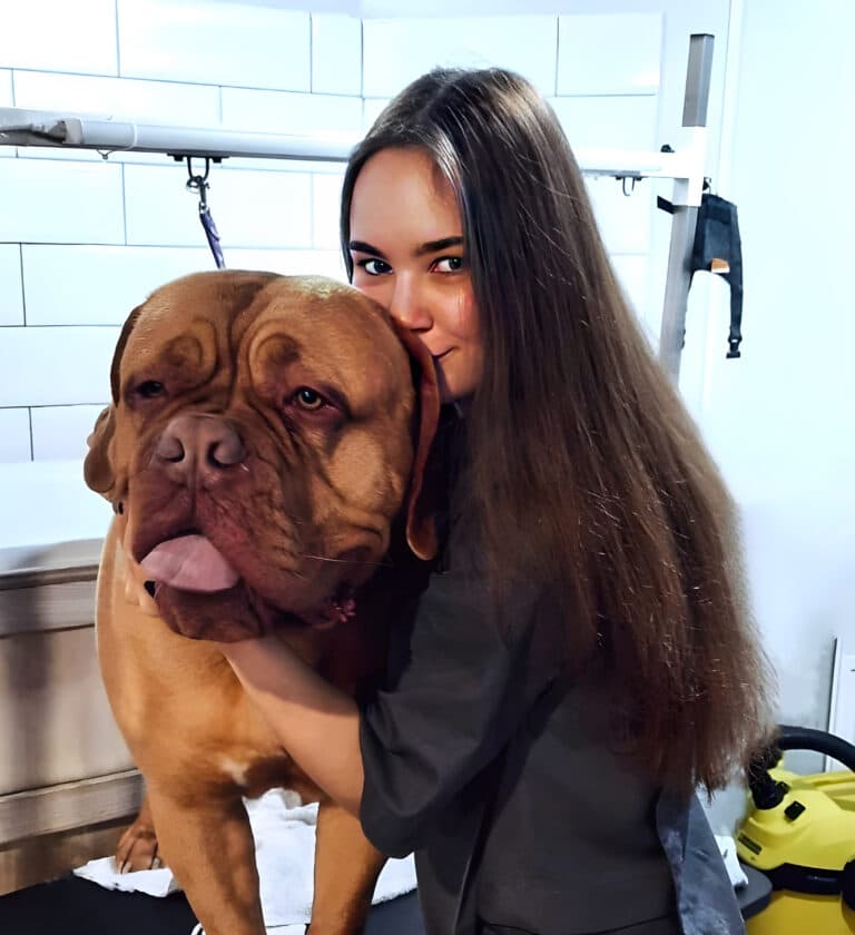 Дівчина з довгим волоссям обіймає за голову великого гладкошерстого собаку у ванні