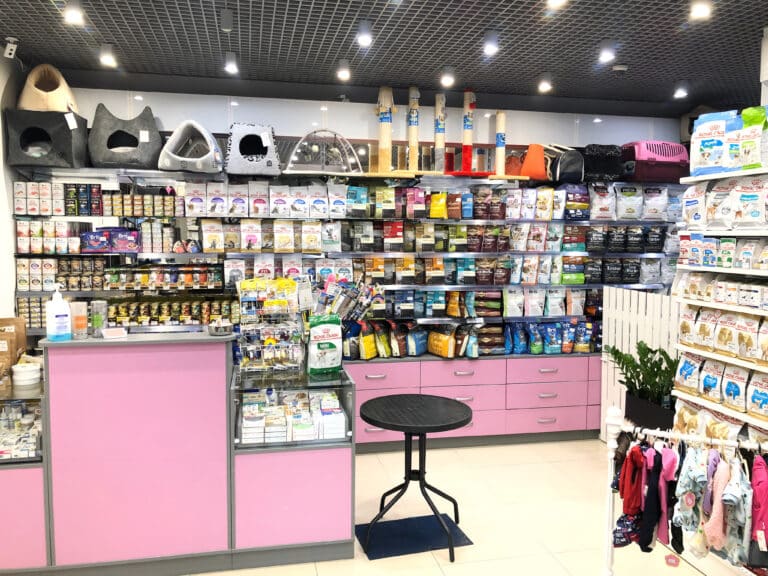 Асортимент корму в зоомагазині з рожевими меблями та бежевою підлогою