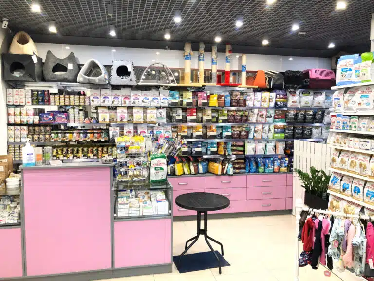 Асортимент корму в зоомагазині з рожевими меблями та бежевою підлогою