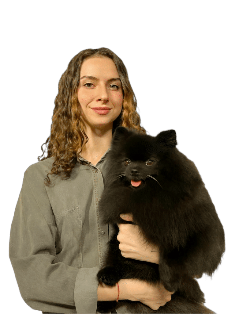 Дівчина з кучерявим волоссям та в джинсовій сорочці тримає в руках чорного шпіца з гострими вушками