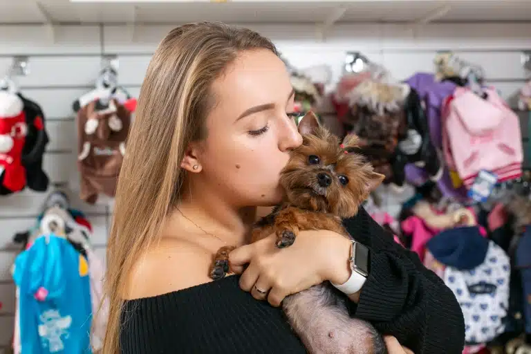 Дівчина з нафарбованими бровами цілує у щічку йорка з короткою шерстю