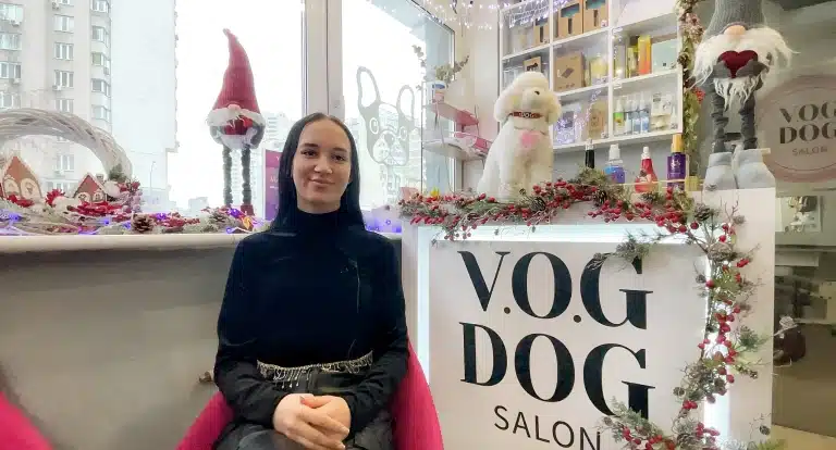 Дівчина з чорним рідким волоссям сидить біля стійки адміністратора в грумінг салоні