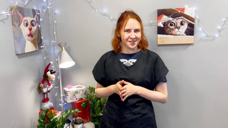 Дівчина з рудим волоссям склала перед собою пальці рук та всміхається