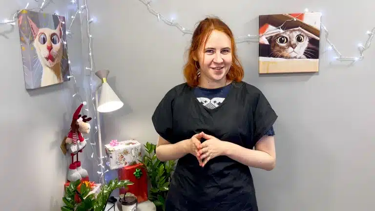 Дівчина з рудим волоссям склала перед собою пальці рук та всміхається