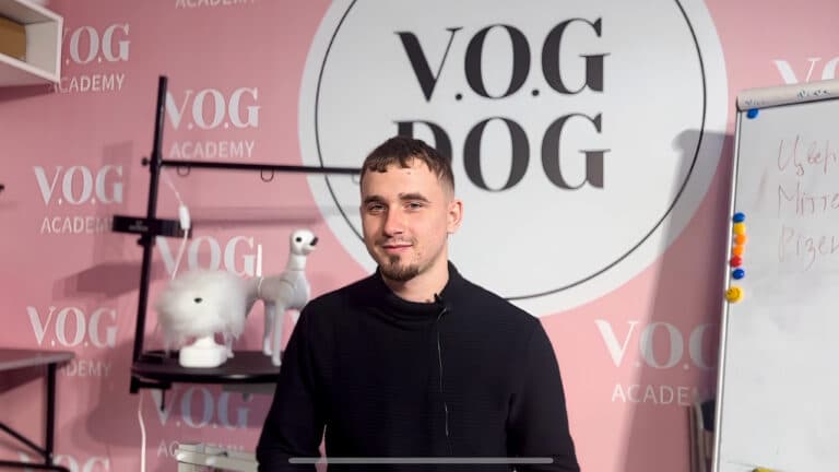 Хлопець з борідкою стоїть перед круглим столом з білим моделдогом