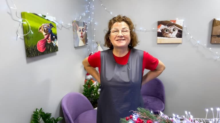 Жінка з коротким волоссям вдягла окуляри, червону футболку та сірий фартух