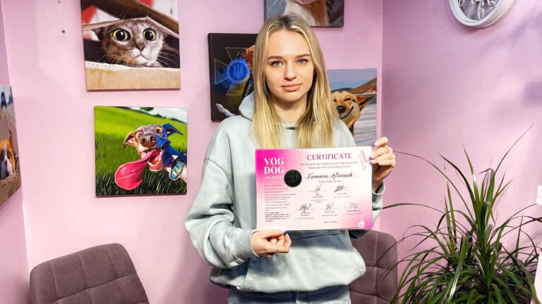 Дівчина зі світлим волоссям тримає в руках рожевий сертифікат Академії грумінгу біля зеленого вазона