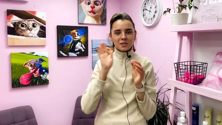 Дівчина в бежевій флісці з прикріпленим мікрофоном щось розповідає, активно жестикулюючи