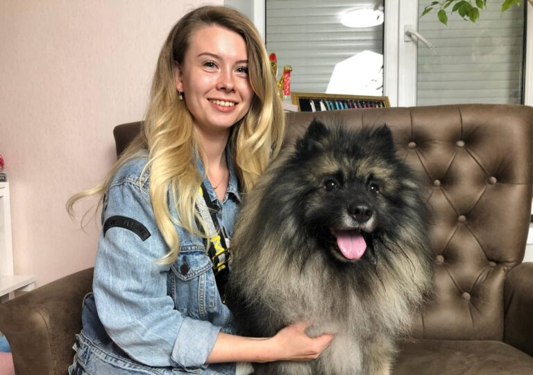 Дівчина в джинсовій куртці сидить на коричневому дивані з вульфшпіцом