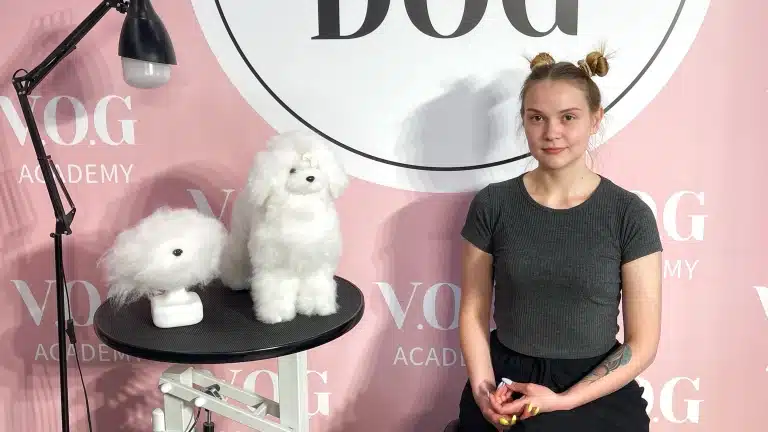 Дівчина з гульками на голові склала разом руки, сидячи на стільці