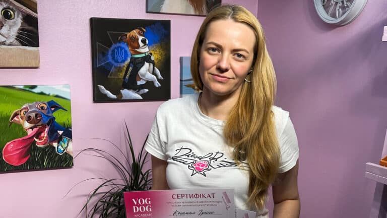 Дівчина з круглими сережками та білій футболці тримає в руках сертифікат на її ім'я