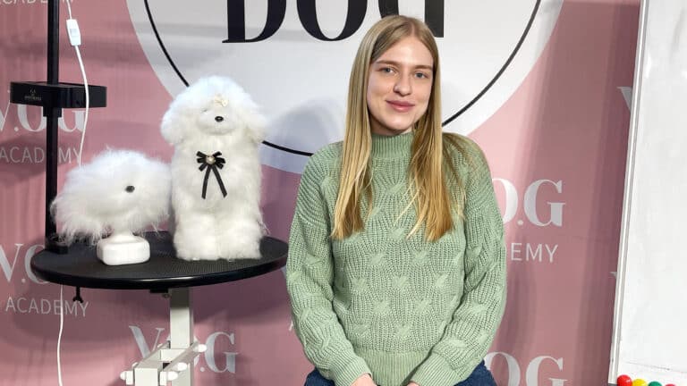 Світла дівчина в зеленому теплому светрі сидить біля моделей для стрижки зі штучним хутром