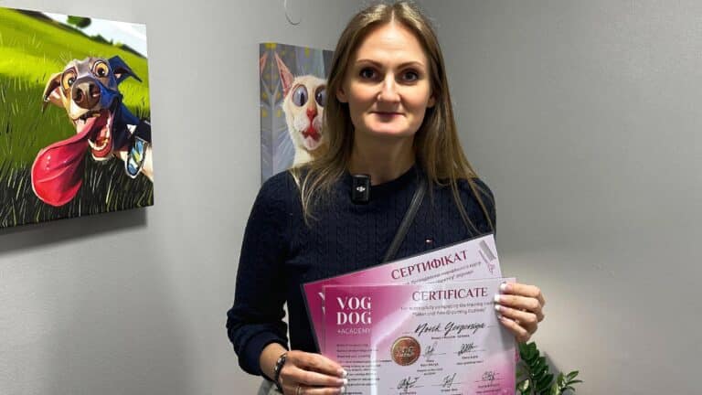 Праворуч від дівчини, що тримає в руках сертифікати, висить картинка веселого собаки