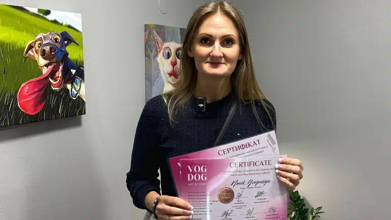 Праворуч від дівчини, що тримає в руках сертифікати, висить картинка веселого собаки