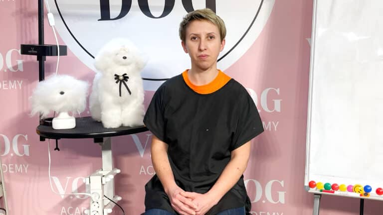 Дівчина з коротко підстриженим волоссям сидить біля дошки, склавши руки