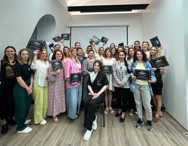 Позаду дівчини в чорно-білій формі зібрались вдячні учні з чорними сертифікатами в руках