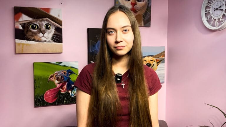 На шиї дівчини в бордовій футболці висить хрестик