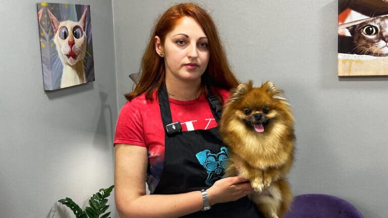 Дівчина з рудим волоссям та в червоній футболці тримає коричневого шпіца