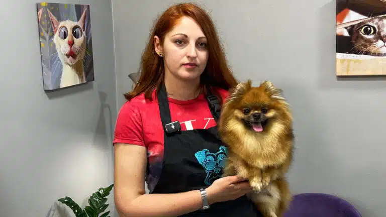 Дівчина з рудим волоссям та в червоній футболці тримає коричневого шпіца