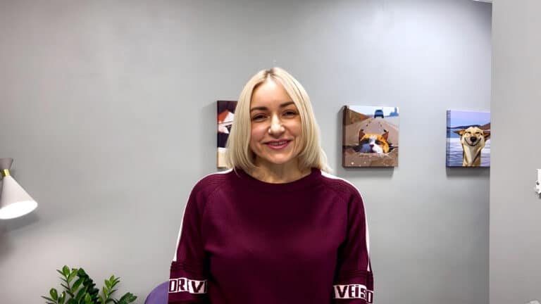 Блондинка сміється, вдягнута в бордовий светр