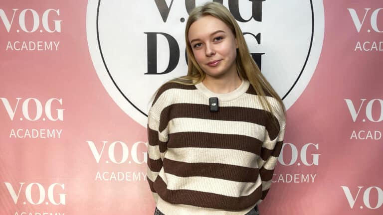 Світла дівчина в смугастому светрі прикриває назву Академії на банері