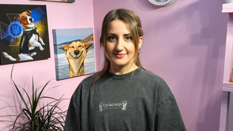 Дівчина з романтичною зачіскою сфотографована поруч з картинами собак, що висять на стіні