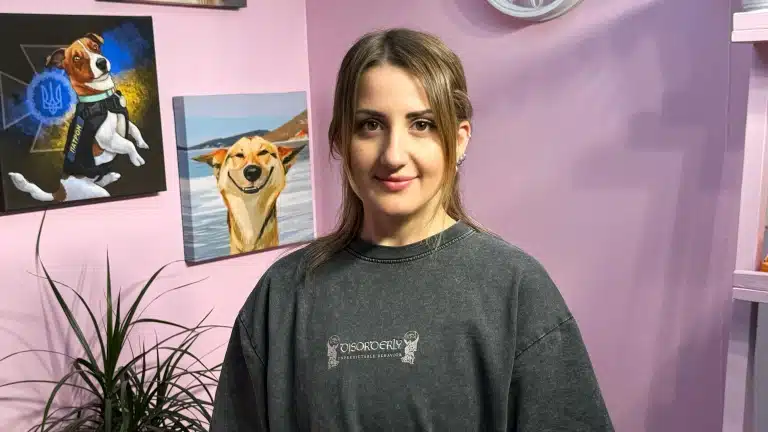 Дівчина з романтичною зачіскою сфотографована поруч з картинами собак, що висять на стіні