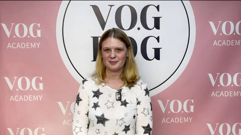 Дівчина в светрі з зірковим принтом стоїть перед банером Академії