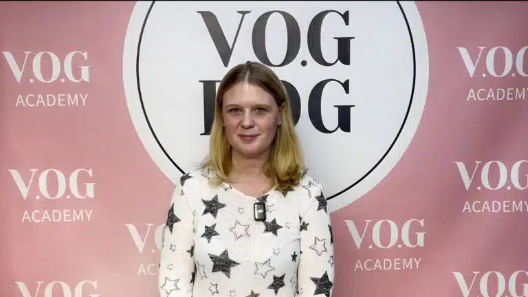 Дівчина в светрі з зірковим принтом стоїть перед банером Академії