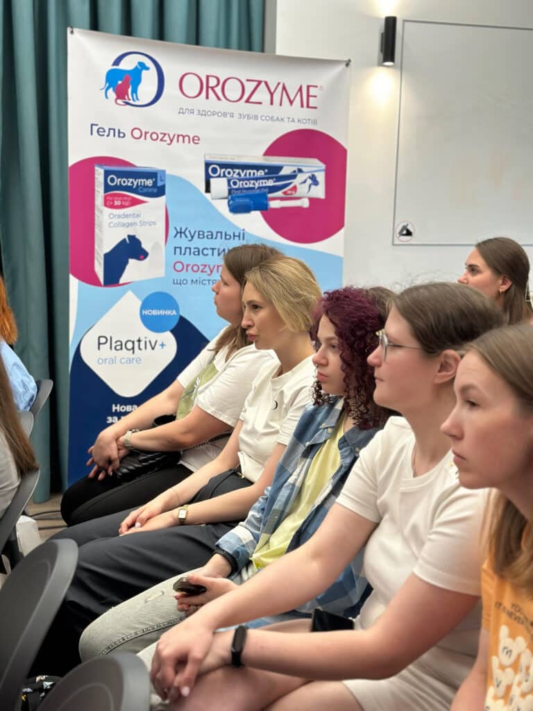 Дівчата уважно слухають лекцію поруч з банером Орозима