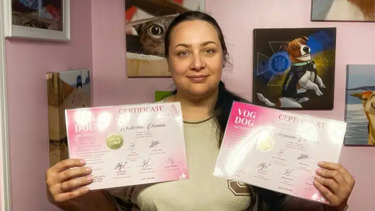 Дівчина з довгим хвостом тримає в руках по рожевому сертифікату про проходження навчання