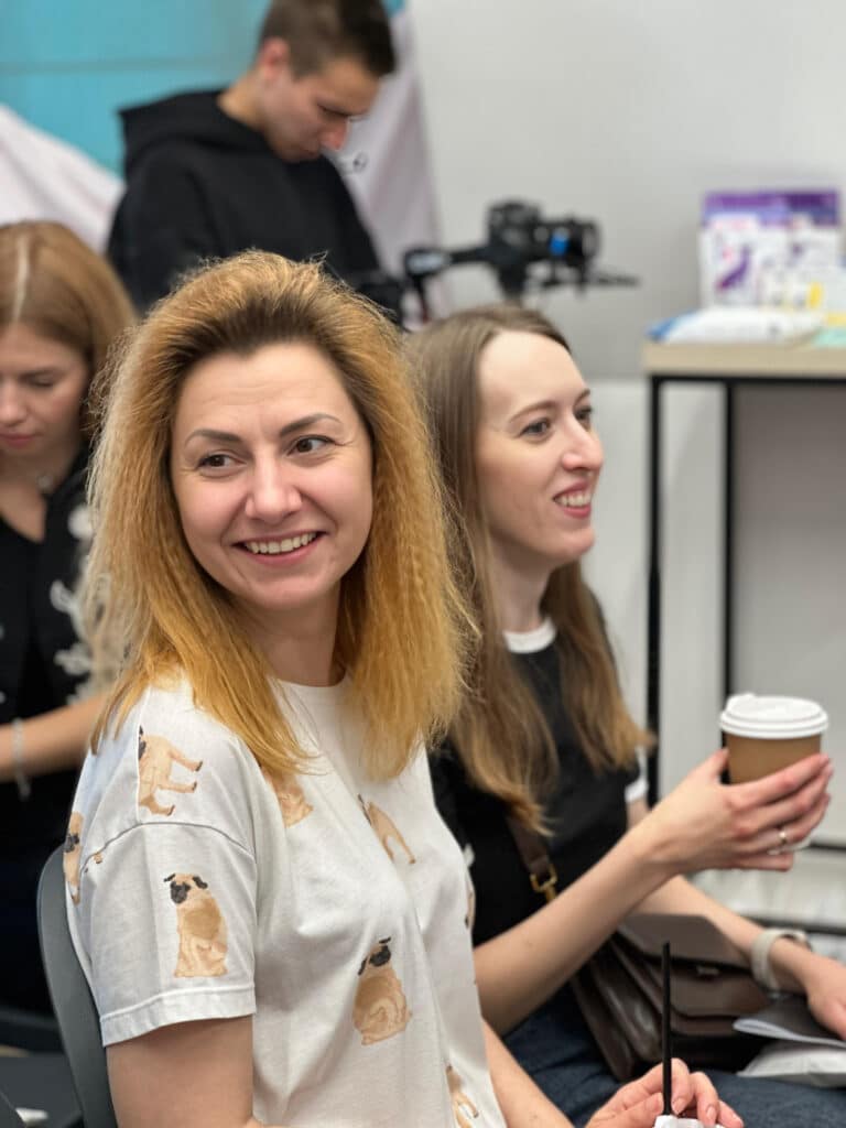 Дівчина з пофарбованим волоссям сидить у футболці з зображенням мопсів